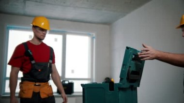 Apartman tamiri - iki işçi ellerinde aletler ve matkapla çantaya doğru yürüyorlar