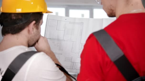 Twee mannen werknemers bespreken een appartement plan op het papier voor het werk — Stockvideo