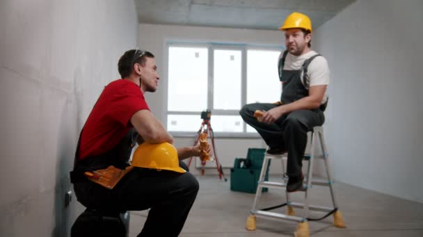 Lägenhet reparation i utkast lägenhet - män arbetstagare som har en paus och äta lunch — Stockvideo