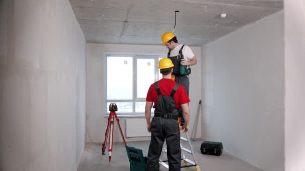 Apartment repair in the room - one man worker passes drill to another — Stock Video