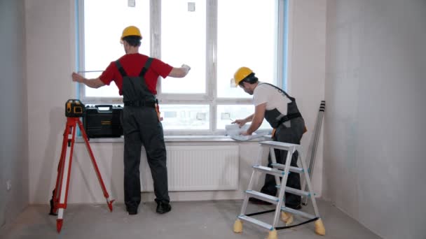 Επισκευή διαμερισμάτων στο δωμάτιο - άνδρες εργαζόμενοι μέτρηση του παραθύρου — Αρχείο Βίντεο