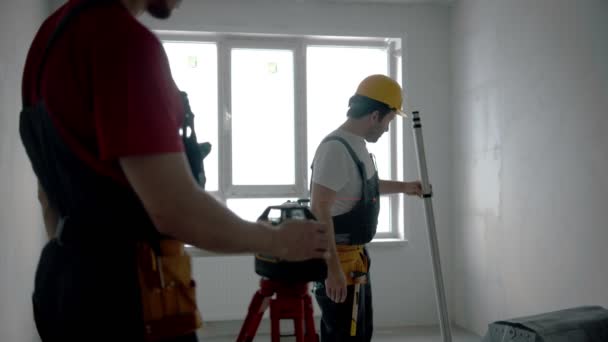 Ремонт на черновике квартиры - два рабочих - лазерная указка и измерительная штука — стоковое видео