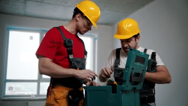 Twee mannen arbeiders trekken hamer en boor uit de zaak — Stockvideo