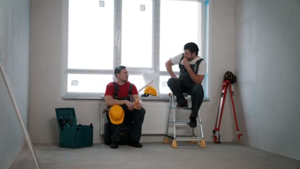 Reparação de apartamento no rascunho de apartamento - homens trabalhadores tendo uma pausa e comer rolo de queijo e maçã — Vídeo de Stock