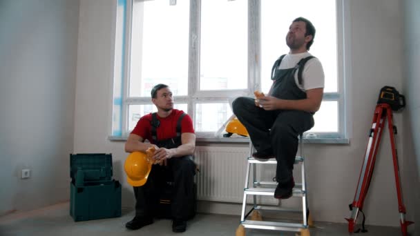 Men workers having a break and eating cheesy roll and apple — Stok video