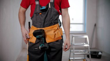 A young man worker wearing a tool belt