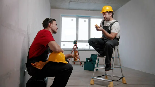 Appartement reparatie in ontwerp appartement - mannen werknemers met een pauze en het eten van lunch in de kamer — Stockfoto