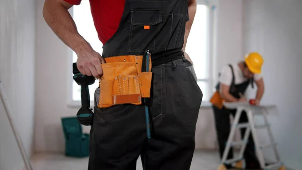 A young man worker putting on a tool belt — Stockfoto