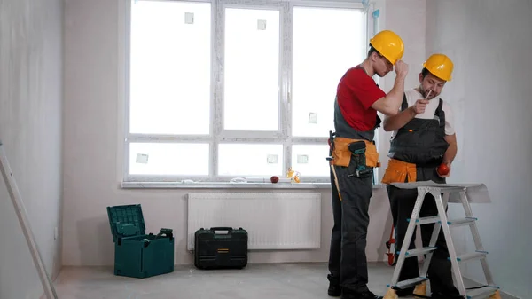 Appartement reparatie - twee mannen werknemers bespreken een appartement plan — Stockfoto