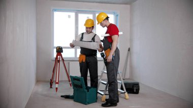 Apartment repair - two men workers discussing an apartment plan before working on it