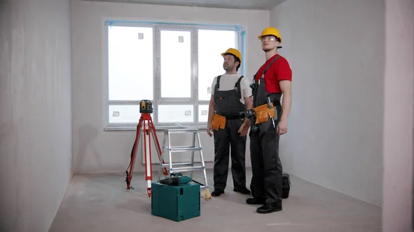 Appartement reparatie - twee mannen werknemers kijken rond in de ontwerp-kamer — Stockfoto