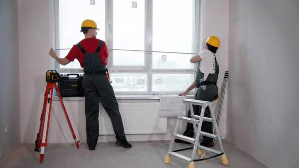 Appartement reparatie in de kamer - twee mannen die het raam meten — Stockfoto