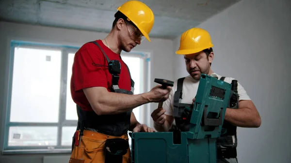 Two men workers pulling instruments out of the case in the draft apartment — Stock Photo, Image