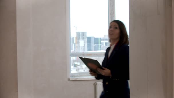 Un agente de bienes raíces que muestra un nuevo proyecto de apartamento a una familia - tocar paredes y hablar — Vídeos de Stock