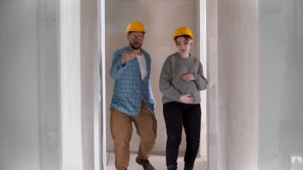 A pregnant woman with her husband dancing in the corridor in their new apartment holding keys — Stock Video