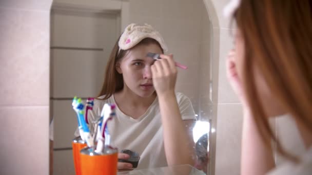 Una joven mujer que se pone una mascarilla en la cara usando un cepillo — Vídeos de Stock