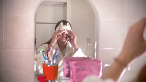 Een jonge vrouw doet haar slaapmasker af in de badkamer — Stockvideo