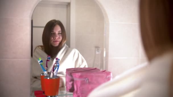 Una mujer joven bailando y cantando con un cepillo de pelo en la mano usando una bata de baño - caminando en el baño — Vídeos de Stock