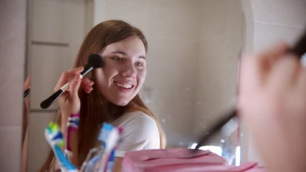 Молода жінка наносить рум'яна на щоки — стокове відео