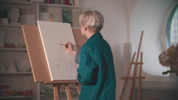 Une jeune femme artiste commence à peindre son croquis en couleur beige dans le studio d'art — Video