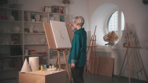En ung kvinna konstnär måla träd i grön färg i konststudio — Stockvideo