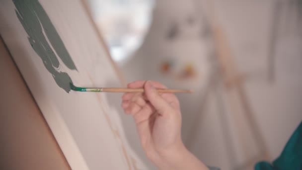 Une jeune jolie femme blonde peignant avec une couleur verte sur la toile — Video