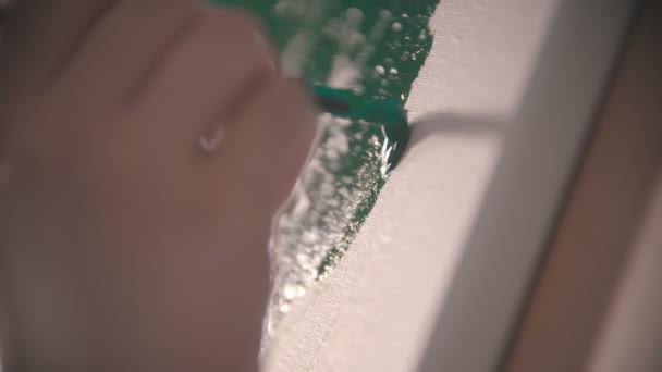 Una joven mujer pintando a mano con un color verde brillante en el lienzo blanco — Vídeos de Stock