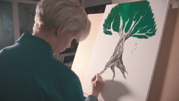 Una joven artista rubia pintando una raíz de árbol en color más oscuro — Vídeos de Stock