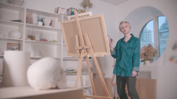 Μια νεαρή ελκυστική γυναίκα καλλιτέχνης ζωγραφίζει ένα κρανίο και άλλες μορφές από το τραπέζι — Αρχείο Βίντεο