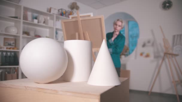 Az asztalon álló figurák a művészeti stúdióban - egy nő rajzolja ezt a kompozíciót — Stock videók