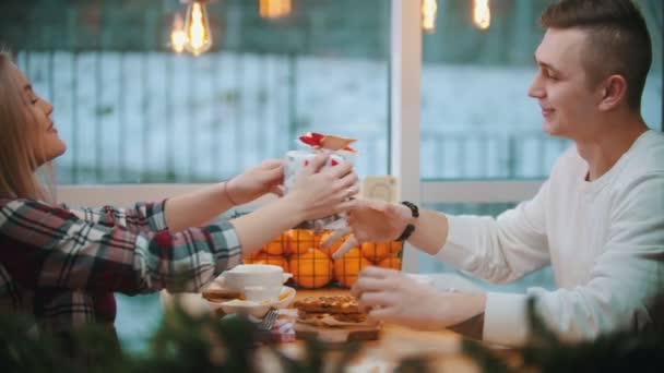 Egy pár a kávézóban - egy nő karácsonyi ajándékot ad a barátjának — Stock videók