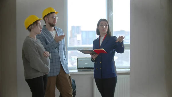 Une femme enceinte avec son mari parlant avec un agent immobilier dans un appartement dans un nouveau bâtiment - homme posant des questions — Photo