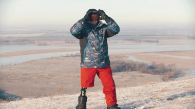 Snowboard - Protez bacaklı bir adam tahtada duruyor ve koruyucu gözlük takıyor.