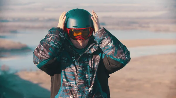 A man snowboarder putting on protective glasses and helmet — ストック写真