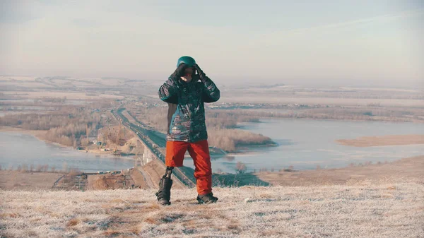 Snowboarding - A man with prosthetic leg standing on the board and putting on protective glasses and helmet — ストック写真