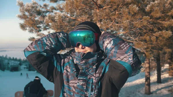 Een man snowboarder zet een beschermende bril op — Stockfoto