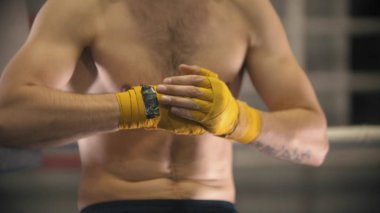 A man boxer with bandaged hands sitting on the ring