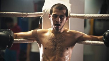 Ağzında diş koruyucusuyla ringde oturan yorgun bir boksör.