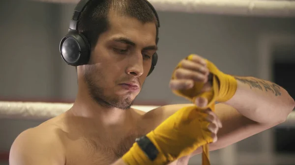 Un hombre boxeador con auriculares vendándose las manos — Foto de Stock