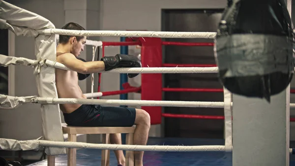 Um homem cansado boxeador sentado no ringue no canto — Fotografia de Stock