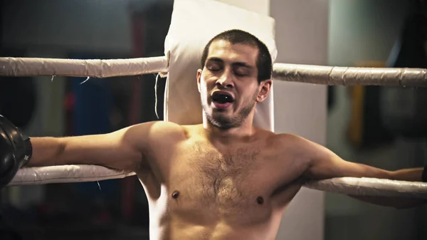 Un boxeador sentado en el ring en la esquina con un protector dental en la boca — Foto de Stock