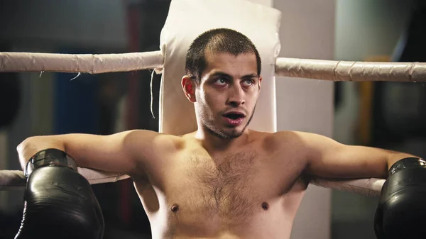 Um homem boxeador sentado no canto do ringue com um protetor de dentes na boca — Fotografia de Stock