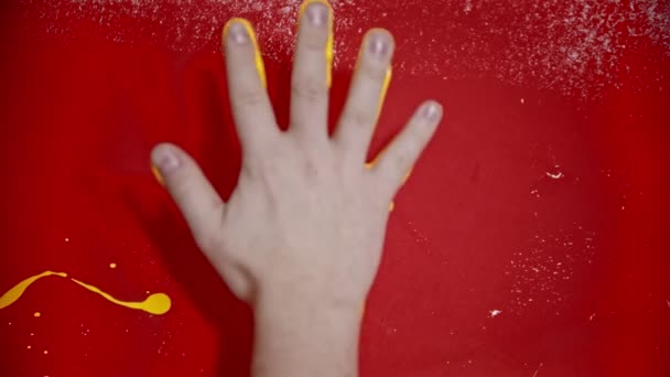 Poner una huella de la mano con un color amarillo brillante en la pared roja — Vídeo de stock