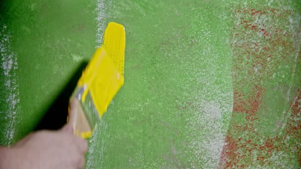 Человек, пишущий "Привет" на зелёной стене с жёлтой краской — стоковое видео