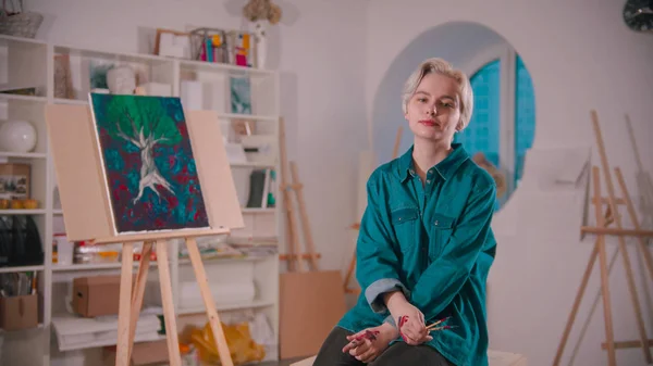 Młoda artystka z krótkimi blond włosami siedząca w pracowni sztuki — Zdjęcie stockowe