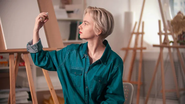 Una joven artista mirando el tubo de pintura dorada —  Fotos de Stock