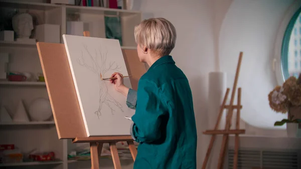 A young woman artist coloring her painting of the tree — 스톡 사진