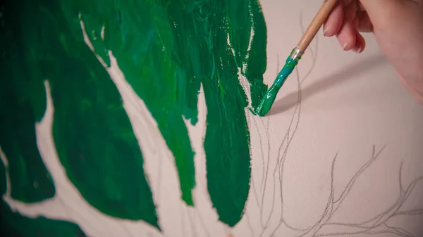 Una joven mujer pintando a mano un árbol verde sobre el lienzo — Foto de Stock