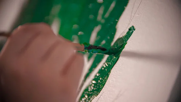 Una joven mujer pintando a mano una corona verde del árbol sobre el lienzo — Foto de Stock