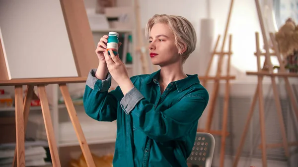 A young woman artist opening up a blue paint tube — 스톡 사진
